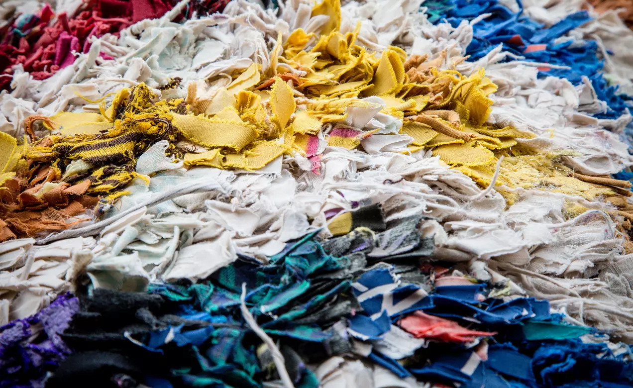 An image of textile scraps in a landfill shows how waste is a real apparel industry issue that requires innovative solutions.